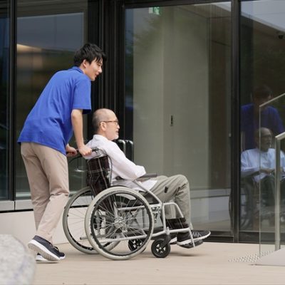Elderly person in wheelchair and caregiver standing on stairs